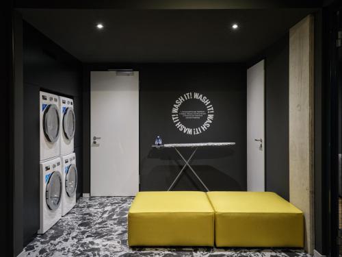 a yellow bench in a laundry room with washing machines at STAYERY Bremen in Bremen