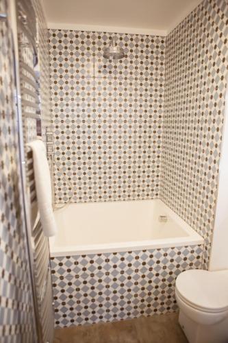 a bathroom with a bath tub and a toilet at Haweswater Hotel in Bampton