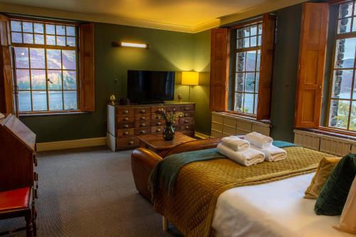 a bedroom with two beds and a tv and windows at Haweswater Hotel in Bampton