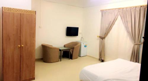 a bedroom with a bed and a desk and a tv at أجنحة مارينا طيبة in Al Madinah