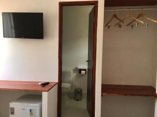 a bathroom with a toilet and a television on a wall at Recanto de Maragogi in Maragogi
