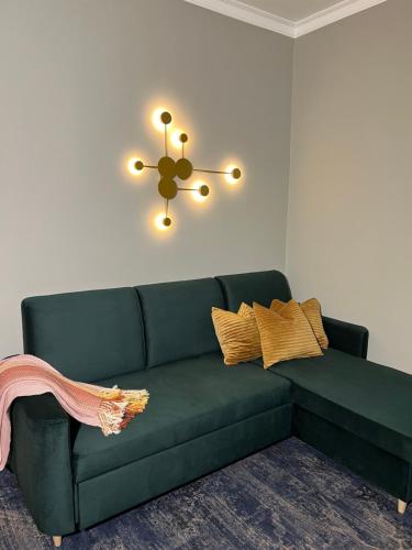 a green couch in a living room with a chandelier at Sadama street Villa in Pärnu