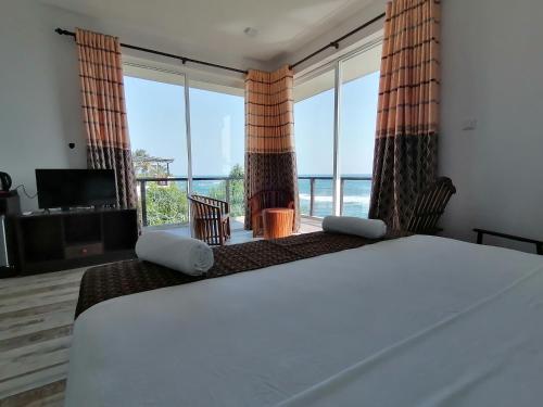 a bedroom with a bed with a view of the ocean at ARA Beach Resort Mirissa in Mirissa