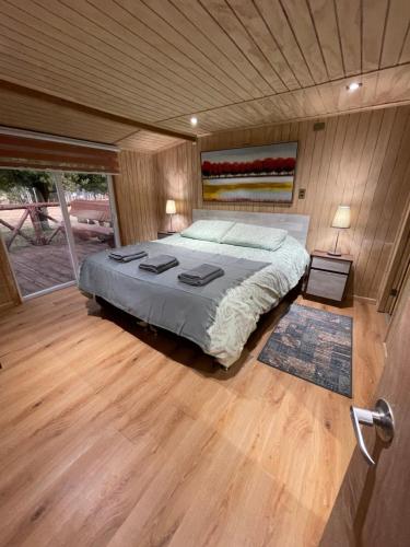 een slaapkamer met een groot bed en een houten vloer bij Cabañas Borde Lindo in San José de la Mariquina