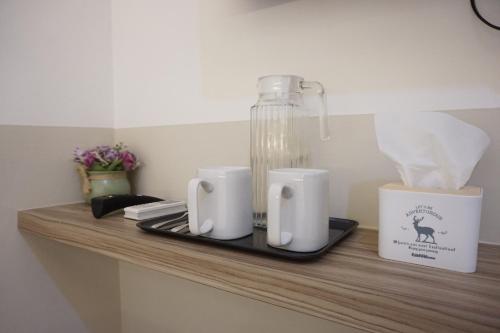 a shelf with two cups and a bottle on it at Aurora House Surabaya in Wijung