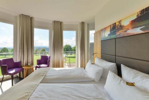 StaufenbergにあるHotel & Golfrestaurant Gut Wissmannshofのベッドと大きな窓が備わるホテルルームです。