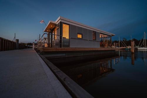 a house on a dock next to a body of water at Schwimmendes Haus - Hausboot Trinity in Peenemünde