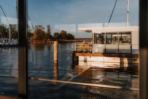 un barco está atracado en un muelle en el agua en Schwimmendes Haus - Hausboot Trinity en Peenemünde