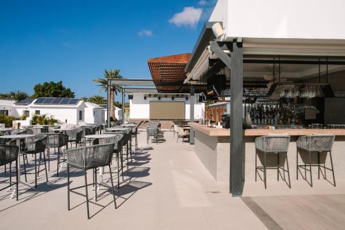 a patio with tables and chairs and a bar at Club Maspalomas Suites & Spa - Adults Only in Maspalomas