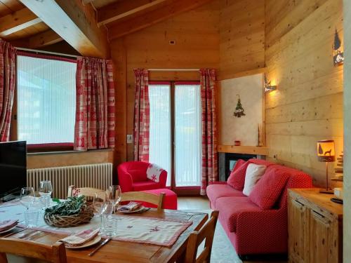 uma sala de estar com uma mesa e cadeiras vermelhas em Chalets Mignon em Limone Piemonte