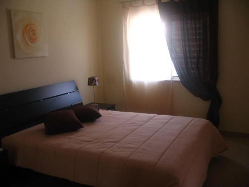 une chambre avec un grand lit avec une fenêtre dans l'établissement Sol e Mar, à Vila Nova De Cacela