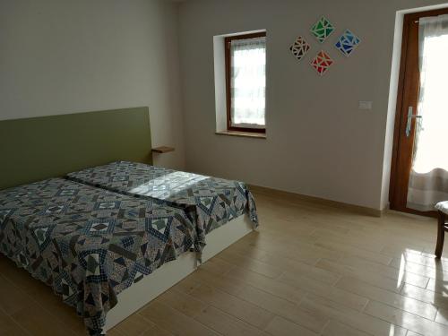 een slaapkamer met een bed en een houten vloer bij Ca' di Burghi 2 in Busca