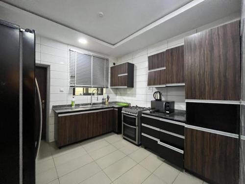 a kitchen with wooden cabinets and a black appliances at Lovely 3-Bed with a Pool next to Four Point in Lagos