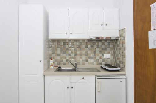 a kitchen with white cabinets and a sink at Margarita in Perissa