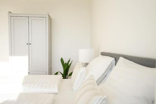 um quarto branco com uma cama com almofadas brancas em Apartment with terrace near Metro Station and Spa em Viena