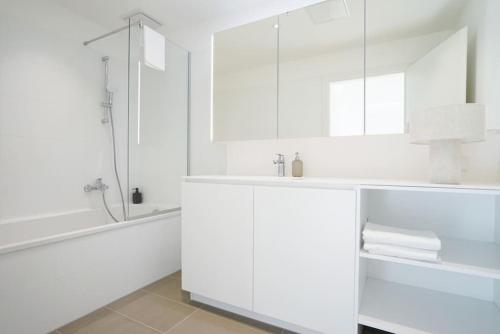 uma casa de banho branca com um chuveiro e um lavatório. em Apartment with terrace near Metro Station and Spa em Viena