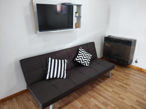 un sofá negro en la sala de estar con TV de pantalla plana en Departamento Yekamush Ushuaia en Ushuaia