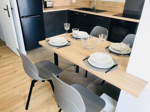 - une table en bois avec des chaises, des assiettes et des verres dans l'établissement Appartement Haut de gamme Créteil, à Créteil