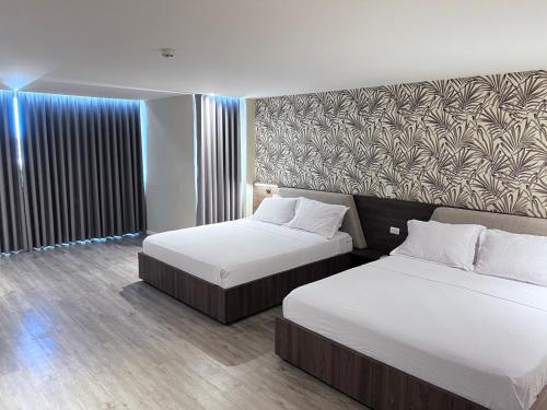 a hotel room with two beds and a wall at Eslait Hotel & Apartamentos in Barranquilla