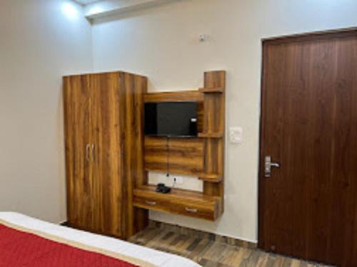 a room with a television and a wooden cabinet at Hotel Taj Sarovar By WB Inn in Agra