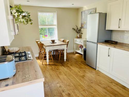 a kitchen with a table and a white refrigerator at Entire 2 bed cottage - Llangwm in Llangwm