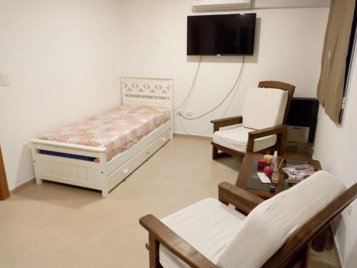 a bedroom with a bed and a chair and a tv at AIRES DE TANDIL in Tandil