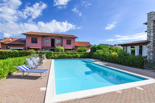 una piscina con due sedie e una casa di Gardaliva - Home & Garden by Garda FeWo a Manerba del Garda