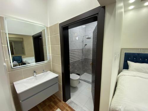 La salle de bains est pourvue d'un lavabo, d'une douche et d'un lit. dans l'établissement Treasury Terrace Apartments, à Wadi Musa
