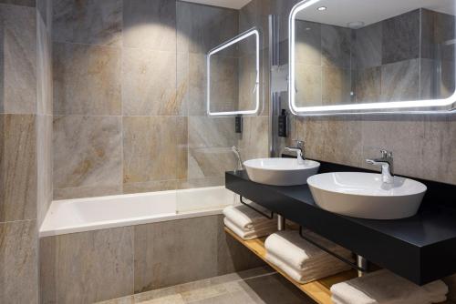 bagno con 2 lavandini, vasca e specchio di HIGALIK HOTEL a Les Menuires