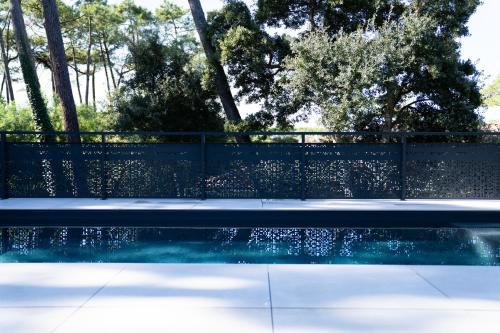una piscina con una valla y árboles en Villa Aréna à Labenne-Océan, en Labenne