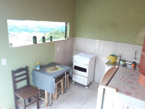 una pequeña cocina con una mesa pequeña y una ventana en Casa Pôr do Sol, en São Thomé das Letras