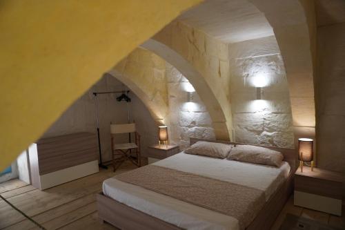 a bedroom with a bed in a stone wall at Il-Mezzanine in Cospicua