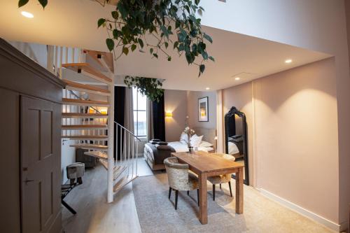 a living room with a dining room table and stairs at Suitehotel Pincoffs in Rotterdam