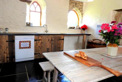 a kitchen with a wooden table with a cutting board at SAUNTON SUNSHINE COTTAGE 3 Bedrooms in Braunton