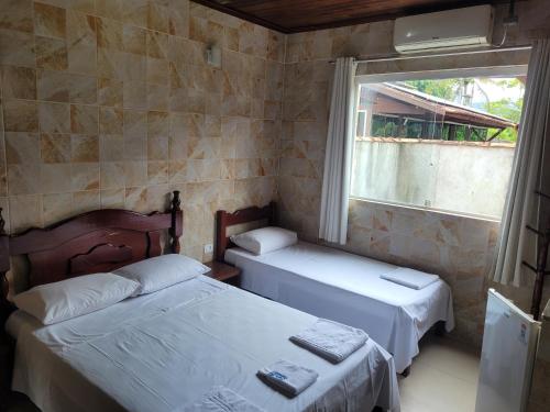 two beds in a small room with a window at Pousada Mar & Sol de Camburi in Camburi