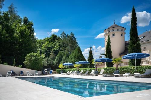a pool with chairs and umbrellas in front of a building at Domaine et Golf de Vaugouard - La Maison Younan in Fontenay-sur-Loing