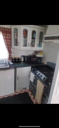 a kitchen with white cabinets and a stove top oven at Beachfront luxury holiday home in Skegness