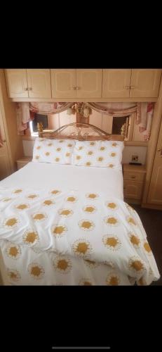 a bed with a white comforter with brown spots on it at Beachfront luxury holiday home in Skegness