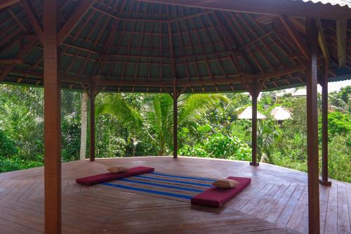 una sala de meditación con 2 colchonetas en el suelo de madera en Ancut Garden en Ubud