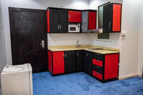 a kitchen with red cabinets and a black door at Ahlin Suites 5 in Riyadh