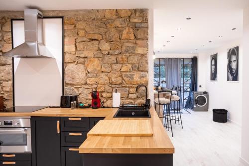 une cuisine avec des placards noirs et un mur en pierre dans l'établissement 
