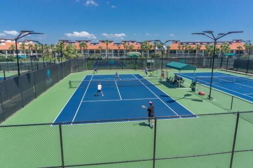 a group of people playing tennis on a tennis court at Edgewater Beach Resort by Panhandle Getaways in Panama City Beach