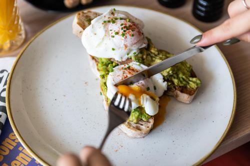 Un plato de comida con un tenedor y huevos encima. en The Coach House, en Potton