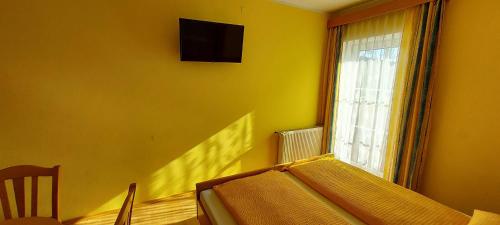 Cette chambre jaune comprend un lit et une fenêtre. dans l'établissement Frühstückspension Koderholt, à Mönichkirchen