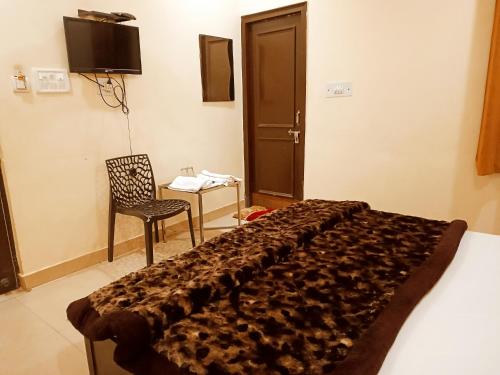 a bedroom with a bed and a chair and a table at Hotel Orange Classic in Rishīkesh