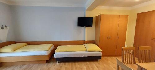 a room with two beds and a tv on the wall at Pension Koderholt in Mönichkirchen