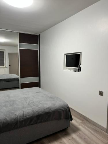 a bedroom with a bed and a flat screen tv at Topoliai Apartament Self check -in in Panevėžys