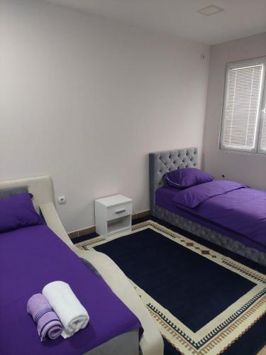1 Schlafzimmer mit 2 Betten mit lila Bettwäsche und einem Teppich in der Unterkunft Comfort in Pirot