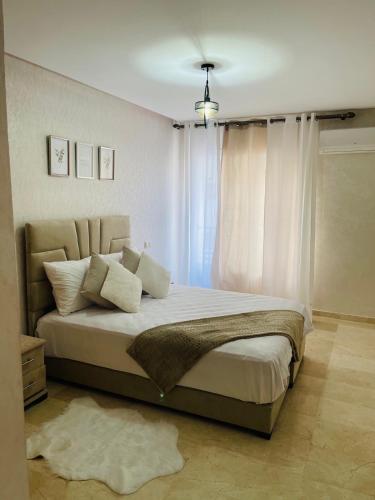 Superbe Appartement au coeur de Casablanca في الدار البيضاء: غرفة نوم بسرير كبير مع ستائر بيضاء