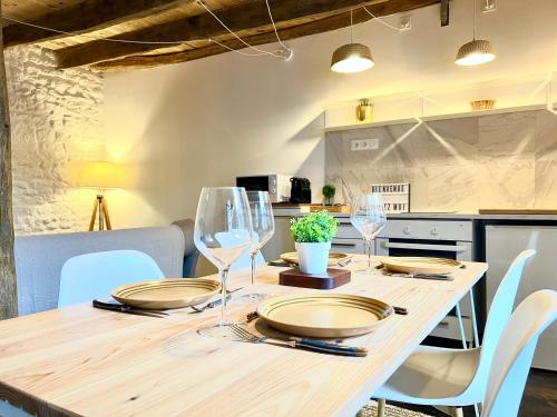 une table en bois avec des assiettes et des verres à vin dessus dans l'établissement L'aphrodite, Magnifique gîte à 10 minutes du Futuroscope, à Jaunay-Clan